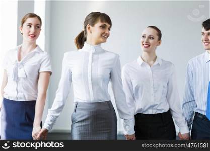Businessteam holding hands. Image of four businesspeople standing in row. Partnership concept