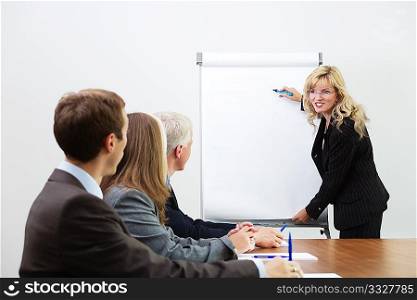Businessteam listening to a coach giving a presentation on a flipchart