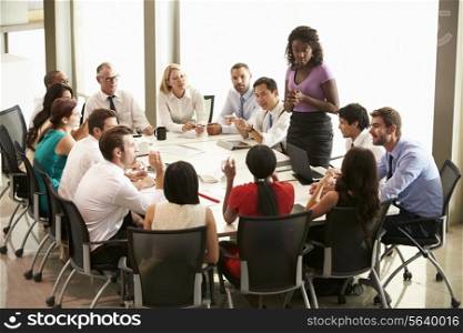 Businesswoman Addressing Meeting Around Boardroom Table