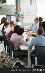 Businesswoman Addressing Meeting Around Boardroom Table