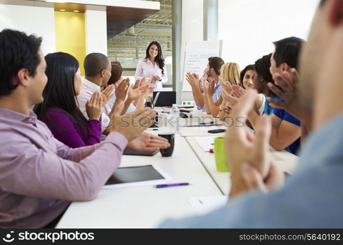 Businesswoman Addressing Meeting Around Boardroom Table