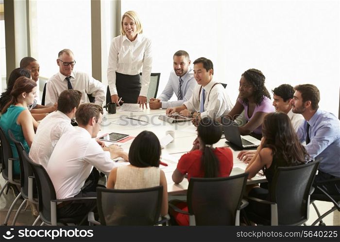 Businesswoman Addressing Meeting Around Boardroom Table