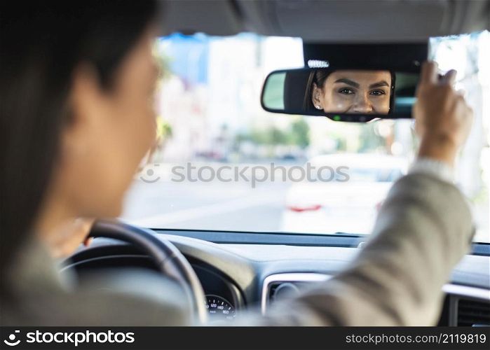 businesswoman adjusting her rear view car mirror