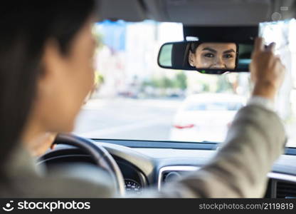 businesswoman adjusting her rear view car mirror