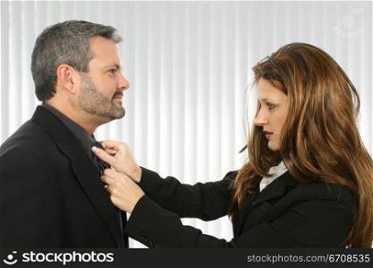Businesswoman adjusting the tie of a businessman