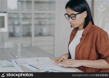 Businesswoman analyzing statistics working on financial project or report. Female employee checking documents, developing business strategy at workspace. Strategic planning, financial data analysis.. Focused businesswoman analyzing statistics working on financial project or report at workspace