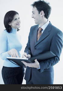 Businesswoman and a businessman holding a personal organizer and looking at each other