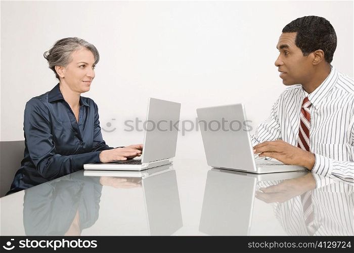 Businesswoman and a businessman working on laptops in an office