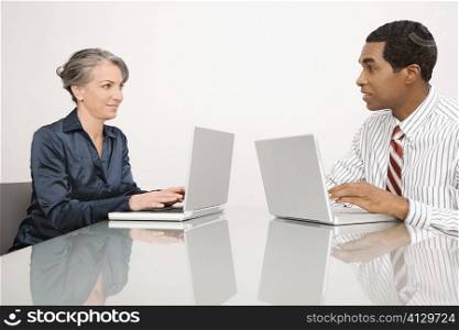 Businesswoman and a businessman working on laptops in an office