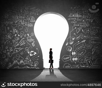 Businesswoman and business plan. Silhouette of businesswoman against black wall with key hole