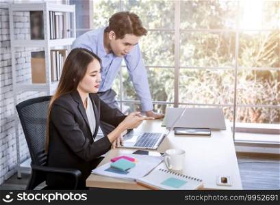 businesswoman and businessman partners discussing positive adult business working together with computer on wooden table and ideas at meeting in office background.
