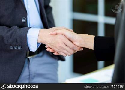 businesswoman and businessman shaking hands at In the office room background after the contract is signed or handshake greeting deal,business expressed confidence embolden and successful concept