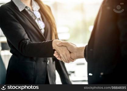 businesswoman and businessman shaking hands at In the office room background after the contract is signed or handshake greeting deal,business expressed confidence embolden and successful concept