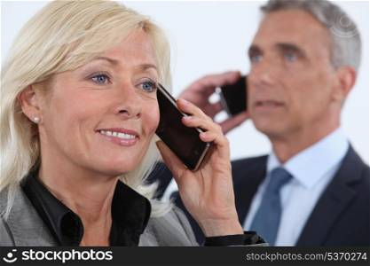 businesswoman and businessman talking on their cells