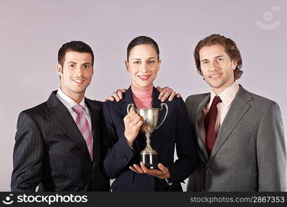 Businesswoman and Businessmen Holding Trophy