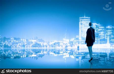 Businesswoman and night city. Businesswoman standing with back against night city panoramic view