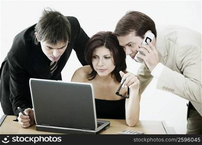 Businesswoman and two businessmen looking at a laptop