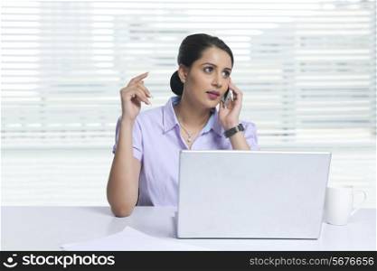 Businesswoman answering mobile phone at office desk