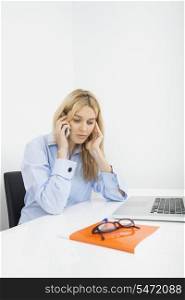 Businesswoman answering smart phone in office