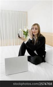 Businesswoman applying makeup with a laptop in front of her