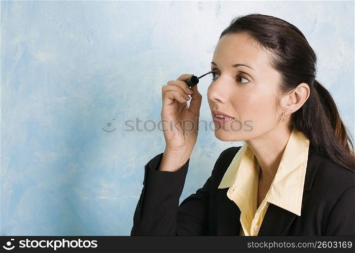 Businesswoman applying mascara on her eyes