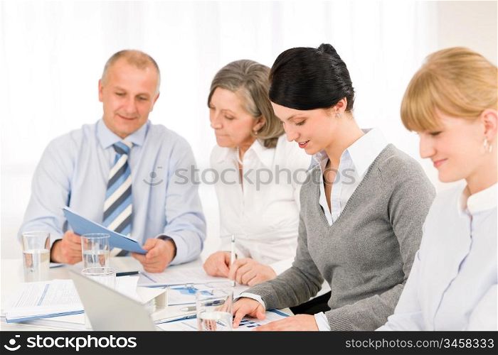 Businesswoman at team meeting with colleagues discussing performance reports