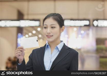 Businesswoman at the airport looking at airplane ticket