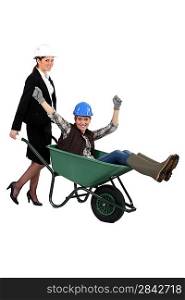 businesswoman carrying a craftswoman in a wheelbarrow