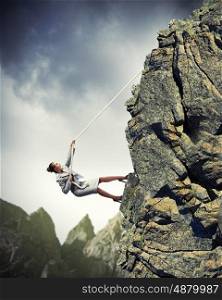 businesswoman climbing mountain. businesswoman climbing steep mountain hanging on rope