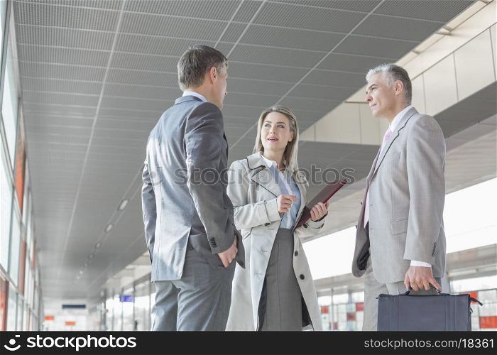 Businesswoman communicating with male colleagues on train platform