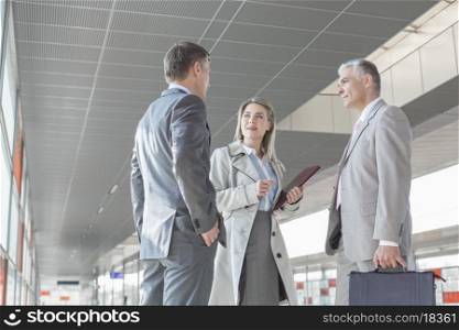 Businesswoman communicating with male colleagues on train platform