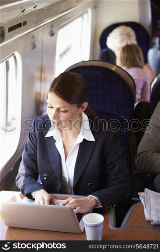 Businesswoman Commuting To Work On Train And Using Laptop