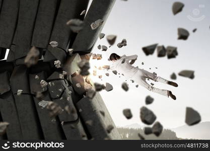 Businesswoman crashing bricks. Determined businesswoman breaking stone bricks with hand punch