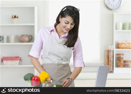 Businesswoman cutting vegetables in kitchen