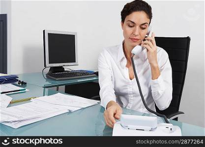 Businesswoman dialling telephone in office
