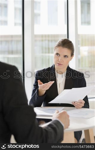 Businesswoman discussing over documents with colleague in office cafe