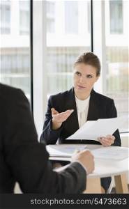 Businesswoman discussing over documents with colleague in office cafe