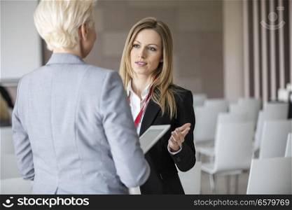 Businesswoman discussing with female colleague in seminar hall