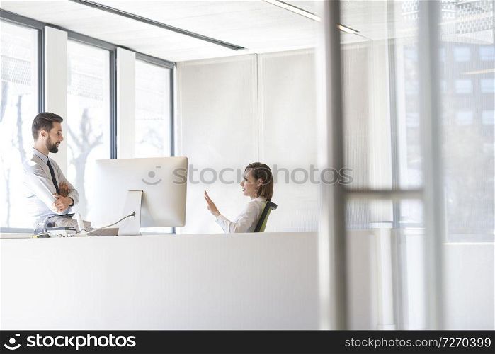 Businesswoman discussing with man at desk in office