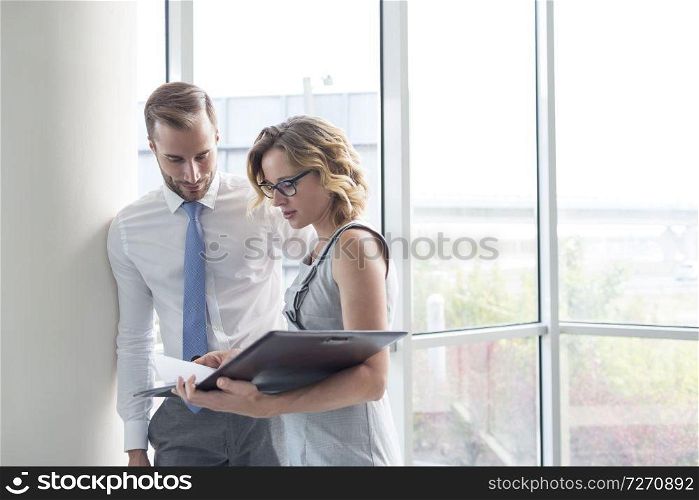 Businesswoman discussing with young businessman over document at new office