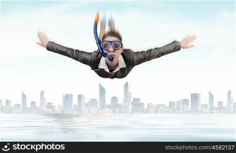 Businesswoman diver. Young businesswoman in suit and diving mask flying in sky