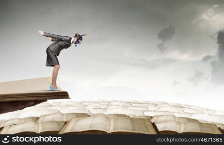 Businesswoman diver. Young businesswoman in suit and diving mask jumping in books