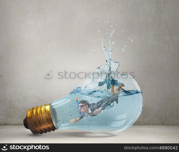 Businesswoman diver. Young businesswoman in suit and diving mask jumping in lightbulb with water