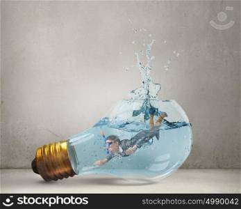 Businesswoman diver. Young businesswoman in suit and diving mask jumping in lightbulb with water