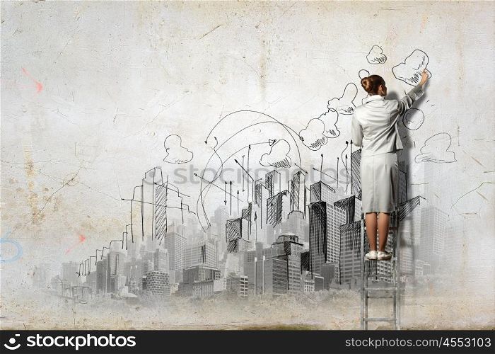 Businesswoman drawing on wall. Businesswoman standing on ladder and drawing sketch on wall