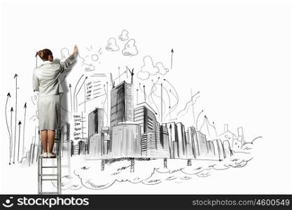 Businesswoman drawing on wall. Businesswoman standing on ladder and drawing sketch on wall