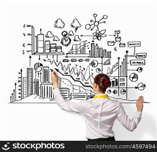 Businesswoman drawing on wall. Businesswoman standing with back drawing business ideas on wall
