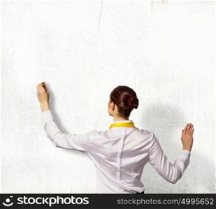 Businesswoman drawing on wall. Businesswoman standing with back drawing on blank wall