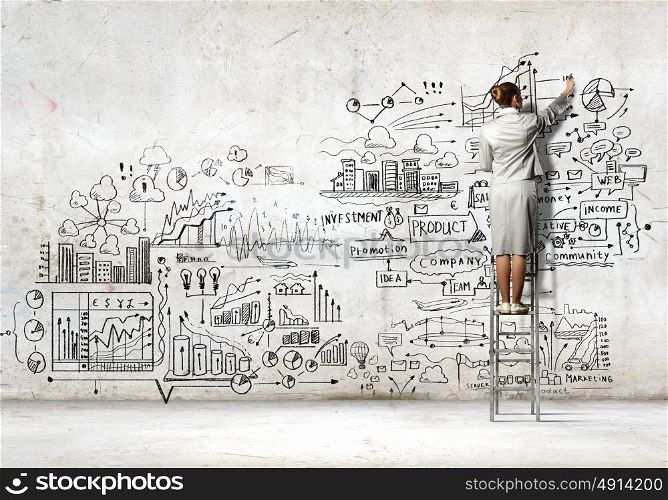 Businesswoman drawing sketch. Back view of businesswoman drawing sketch on wall