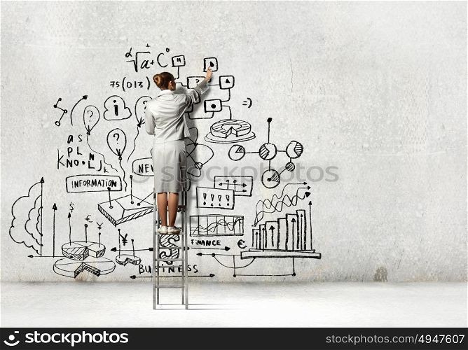 Businesswoman drawing sketch. Back view of businesswoman drawing sketch on wall